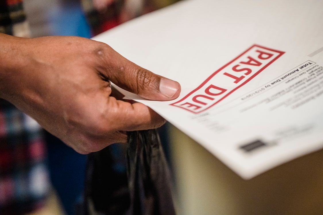 Hand holding past due water bill document